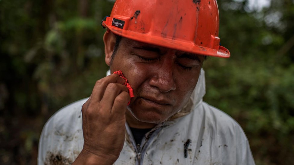 Hombre limpiándose el petróleo de la cara.