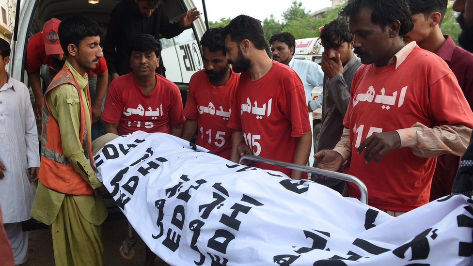 Пакистанские добровольцы переносят труп осужденного убийцы Шафката Хусейна в морг после его казни в Карачи 4 августа 2015 г.