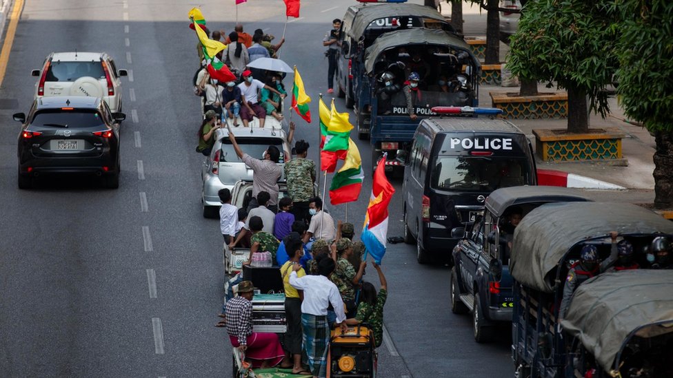 Military supporters drive-by police trucks parked aside the Streets in Yangon.
