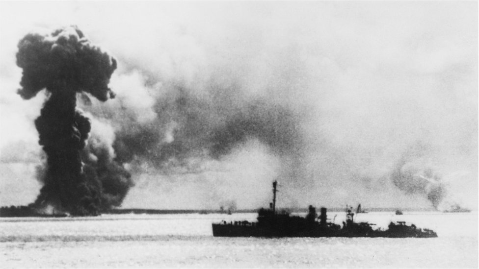 A Japanese air attack on Port Darwin, Australia, during World War II, 1942. In the foreground right is a US destroyer, and behind it (left to right) are the burning remains of an Australian ship, an Australian hospital ship and a British ship.