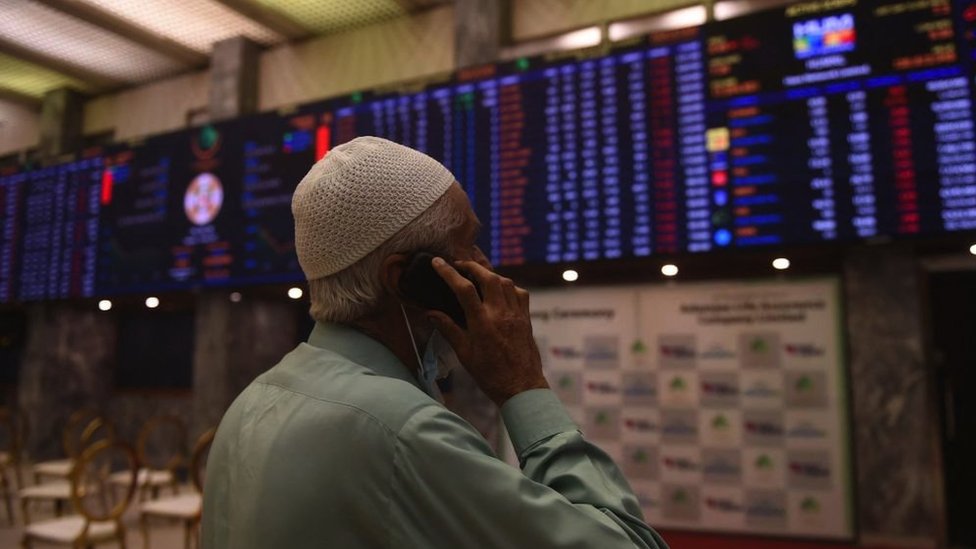 سمسار بورصة يتحدث على هاتفه المحمول وهو يراقب أحدث أسعار الأسهم في بورصة باكستان (PSX) في كراتشي في 7 مارس 2022