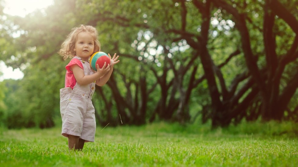 Маленькая девочка с мячом в поле