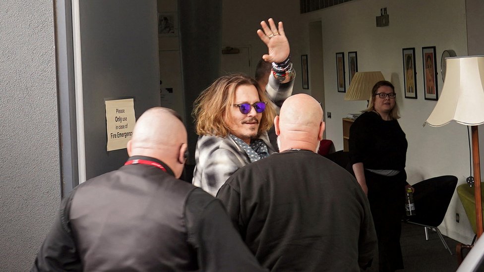 Johnny Depp saluda seguido por escoltas