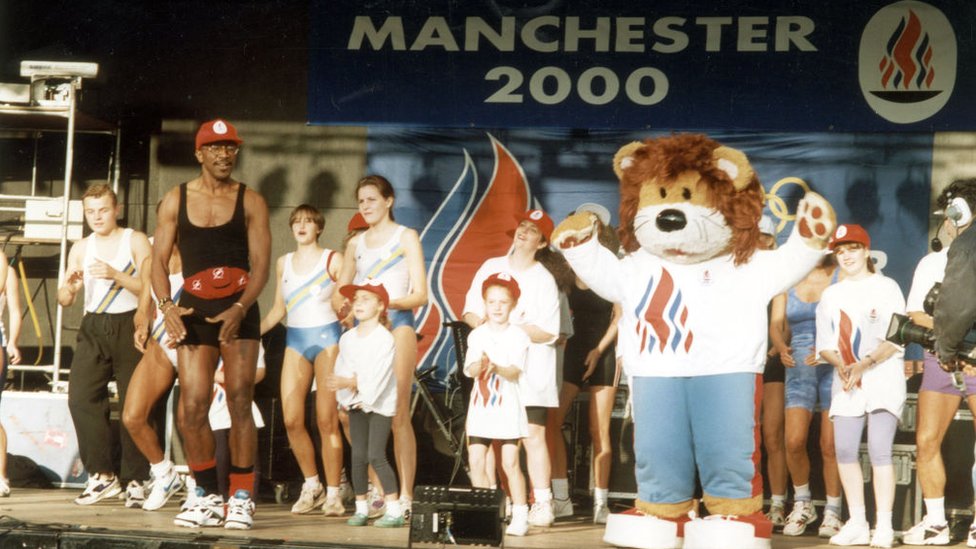 Мистер Мотиватор, талисман и несколько детей на сцене на мероприятии в Манчестере в тот день, когда в 1993 году был объявлен город-организатор Олимпийских игр 2000 года