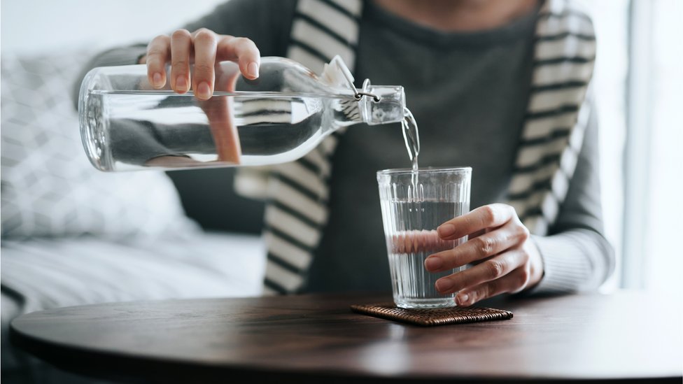 Mulher colocando água no copo