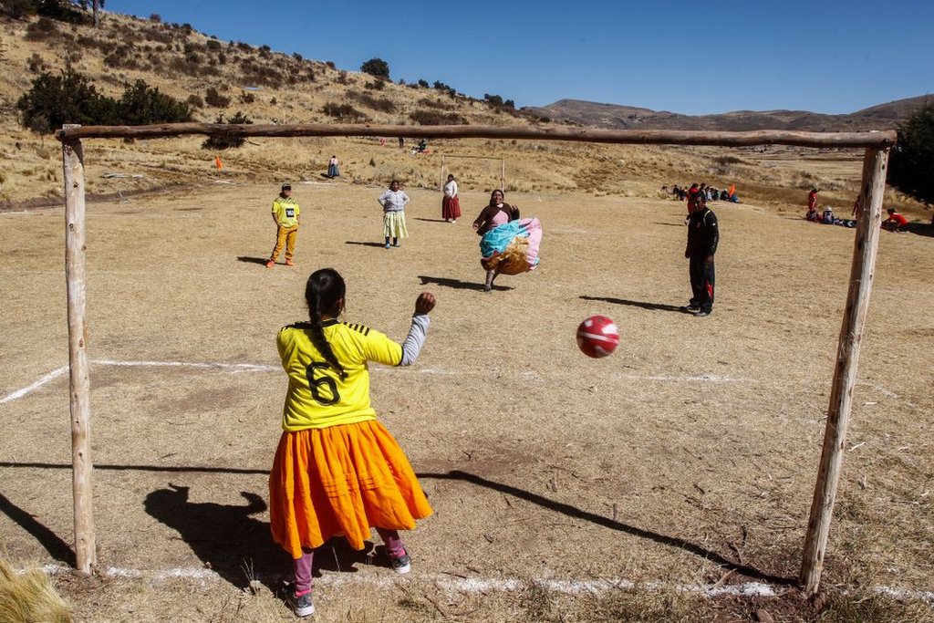 Mujeres indígenas aymaras juegan al fútbol ien Perú con camisetas de todos los colores.
