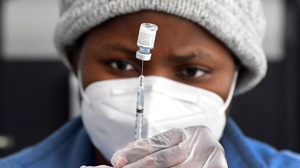 A nurse fills a syringe with vaccine from a vial