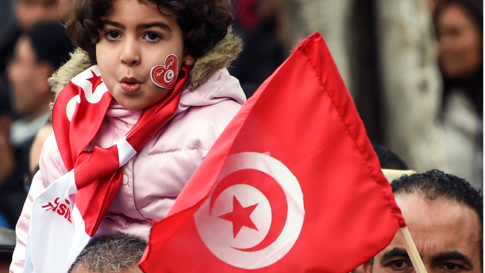 طفلة تمسك علم تونس على أكتاف أبيها
