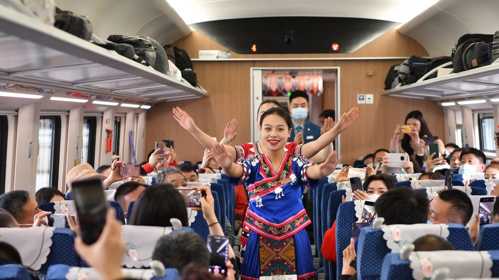 Attendants wearing national costumes perform on the first train of the China-Laos Railway, a 1,035-km electrified passenger and cargo railway connecting Kunming in southwest China's Yunnan Province with the Lao capital Vientiane, on December 3, 2021 in Kunming, Yunnan Province of China.