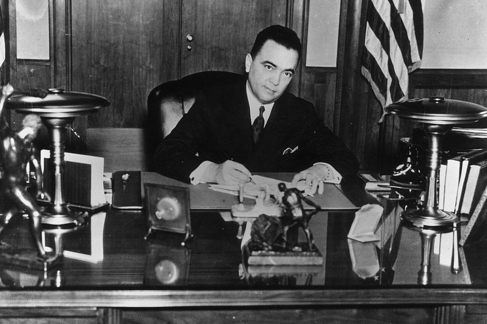 J. Edgar Hoover firma un documento en su escritorio. Foto circa 1935.