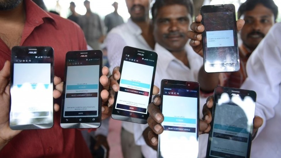Индийские водители Uber демонстрируют мобильные телефоны, предоставленные им компанией во время однодневной голодовки против транспортной службы со штаб-квартирой в США в Хайдарабаде 28 августа 2015 года.