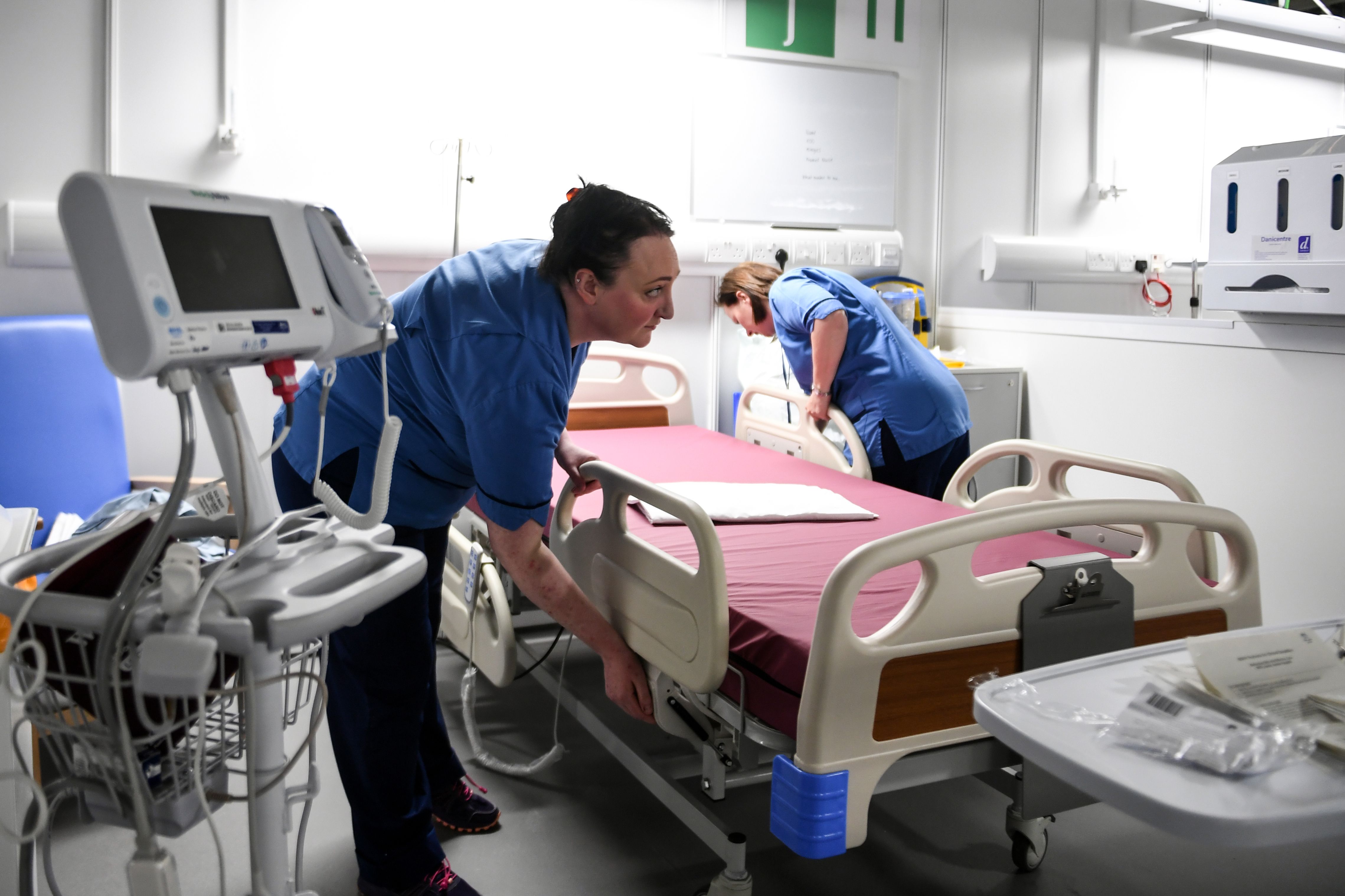 تقوم الممرضات بإعداد السرير أمام جهاز التنفس الصناعي