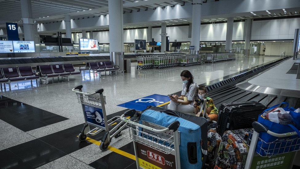 香港國際機場一號客運大樓一對母子坐在空蕩的抵達行李大廳旁等候（9/7/2022）