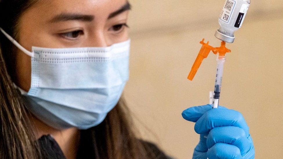 a nurse loads a syringe with vaccine
