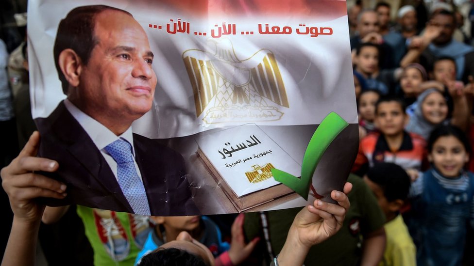 Египтянин держит плакат с надписью: «Голосуйте вместе с нами ... сейчас ... сейчас» на избирательном участке в Менуфии (22 апреля 2019 г.)