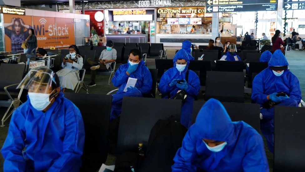 Viajeros con ropas de protección en aeropuerto de Yakarta, Indonesia