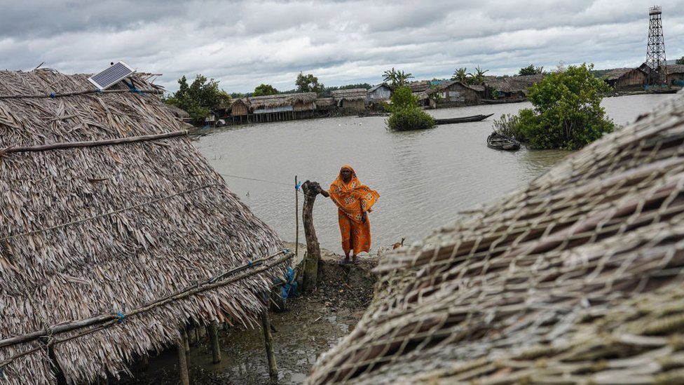 امرأة تقف أمام منزلها الذي أعيد بناؤه عدة مرات في كل مرة يضرب فيها إعصار المنطقة الساحلية لقرية جايماني، في بنغلاديش التي هي واحدة من أكثر البلدان عرضة لتأثيرات تغير المناخ