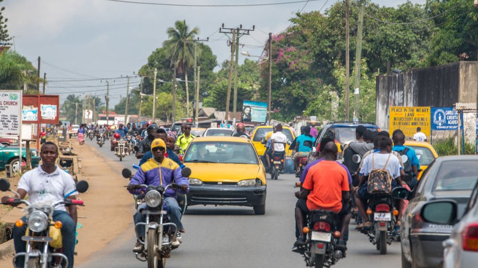 Men ride motorcycles through traffic in Ganta Liberia