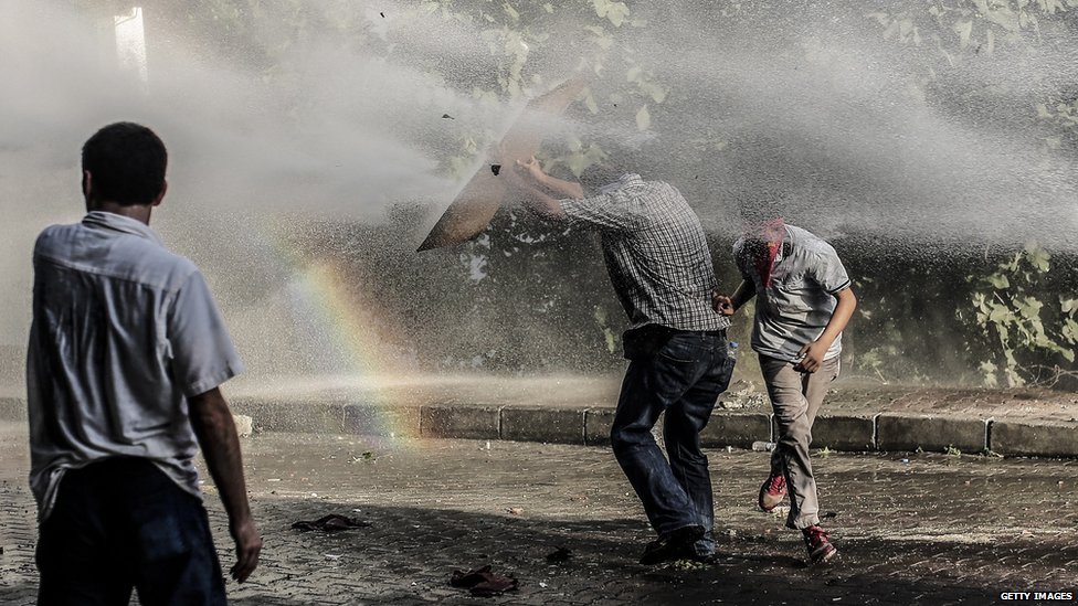 Левые боевики укрываются от водомета во время столкновения с турецкими полицейскими 25 июля