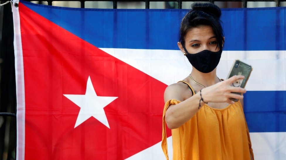 Cubana, frente a la bandera de Cuba.