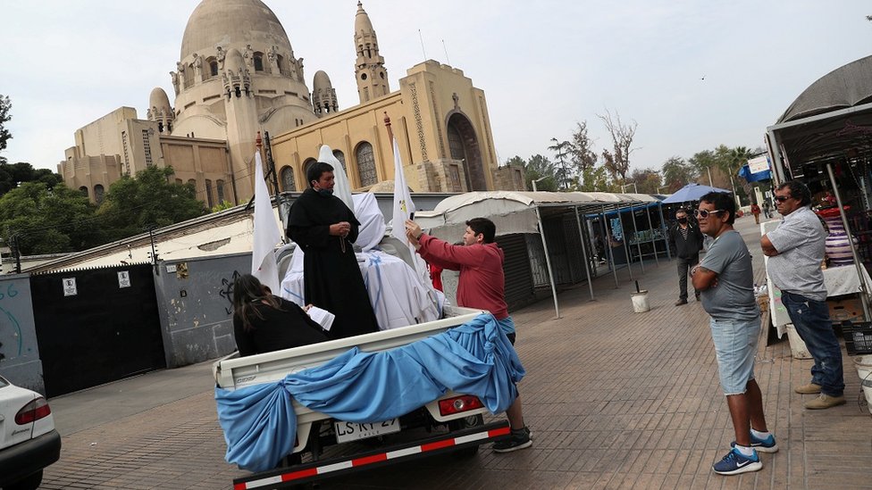 A priest uses a van to give blessings during Easter Saturday in Santiago, Chile