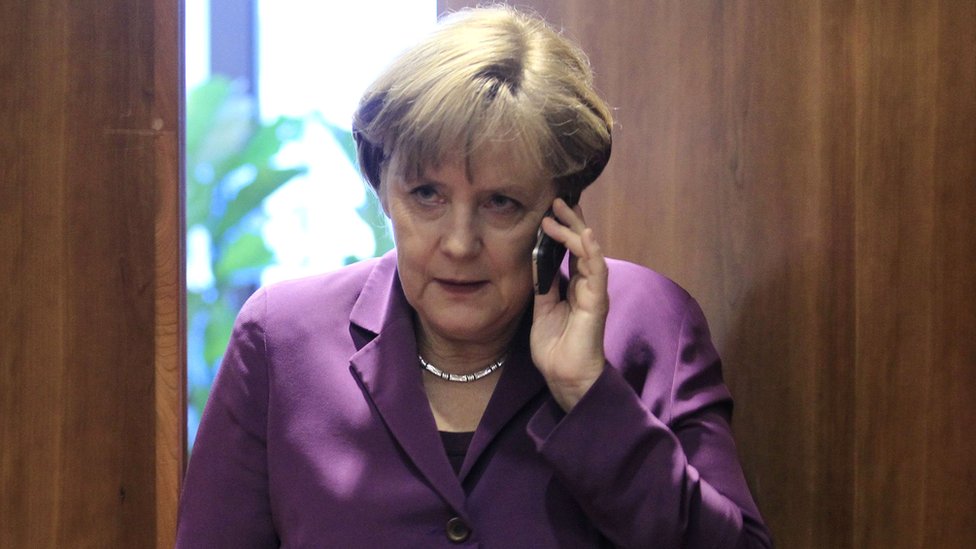 German Chancellor Angela Merkel uses her mobile phone before a meeting at a European Union summit in Brussels, 9 December 2011