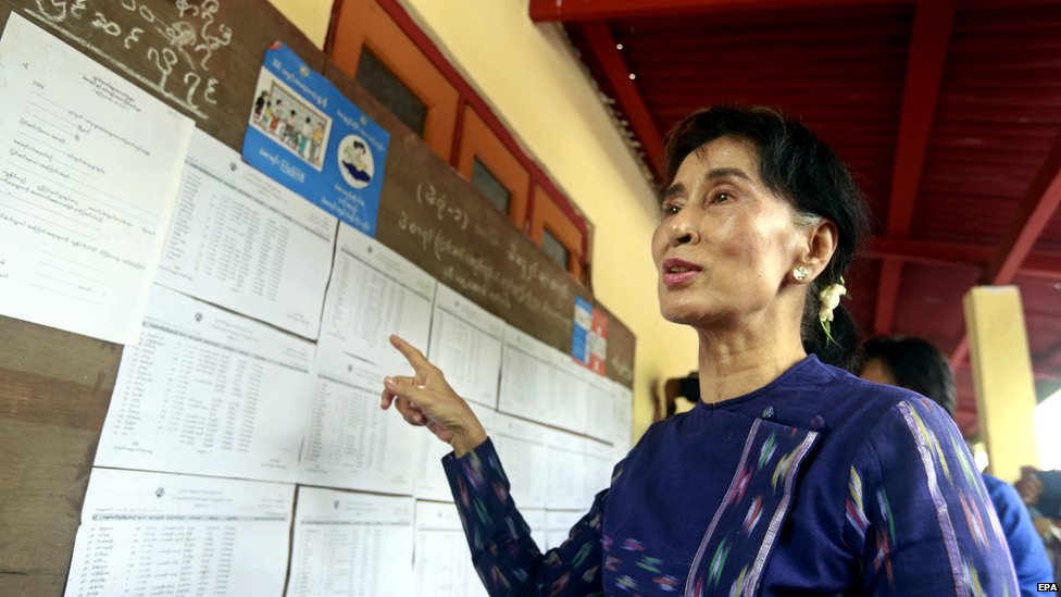 Лидер оппозиции Мьянмы Аунг Сан Су Чжи (C) разговаривает со СМИ, проверяя список избирателей в деревне Вахтейнха в поселке Кавмху, Янгон, Мьянма, 4 июля 2015 г.