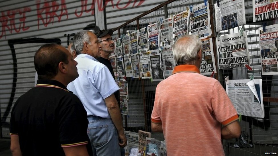 27 июня в Афинах люди читают заголовки газет