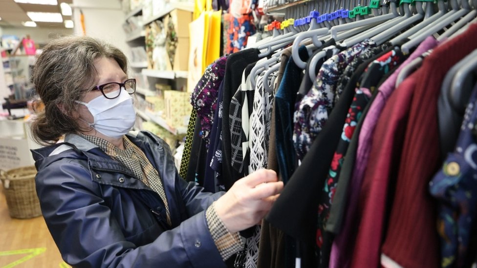 Женщина делает покупки, рассматривает одежду