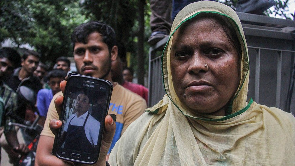 Женщина по имени Джохра показывает на мобильном телефоне фотографию своего шурина Сайдула, работника ресторана