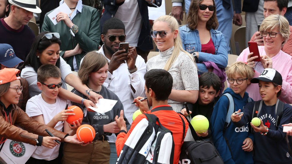 Novak Djokovic firma pelotas ante una multitud.