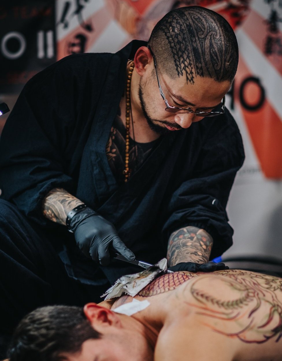 Kensho II works on a customer's tattoo