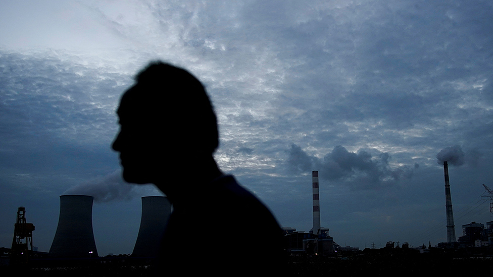 Un hombre pasa frente a una central eléctrica de carbón en Shanghái, China, el 14 de octubre de 2021.