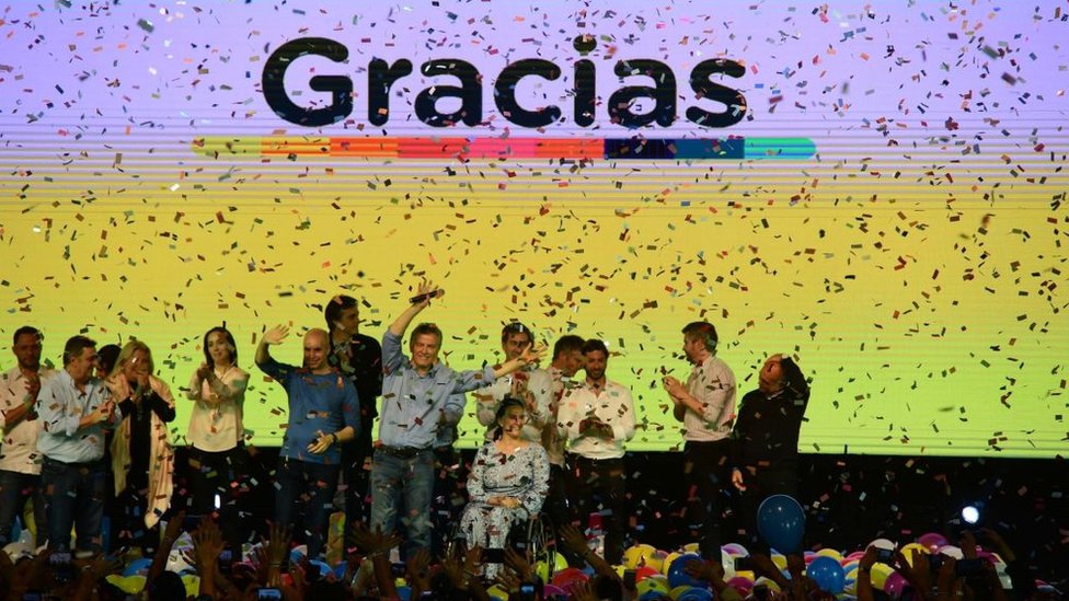Macri celebrando su victoria en las elecciones legislativas detrás de un panel que dice: Gracias