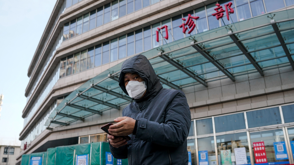 Um homem usando máscara do lado de fora de um hospital em Pequim