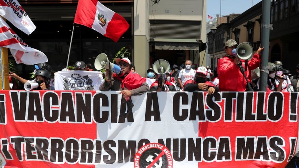 Pessoas com bandeiras e megafones atrás de faixa pedindo 'Vacancia a Castillo'