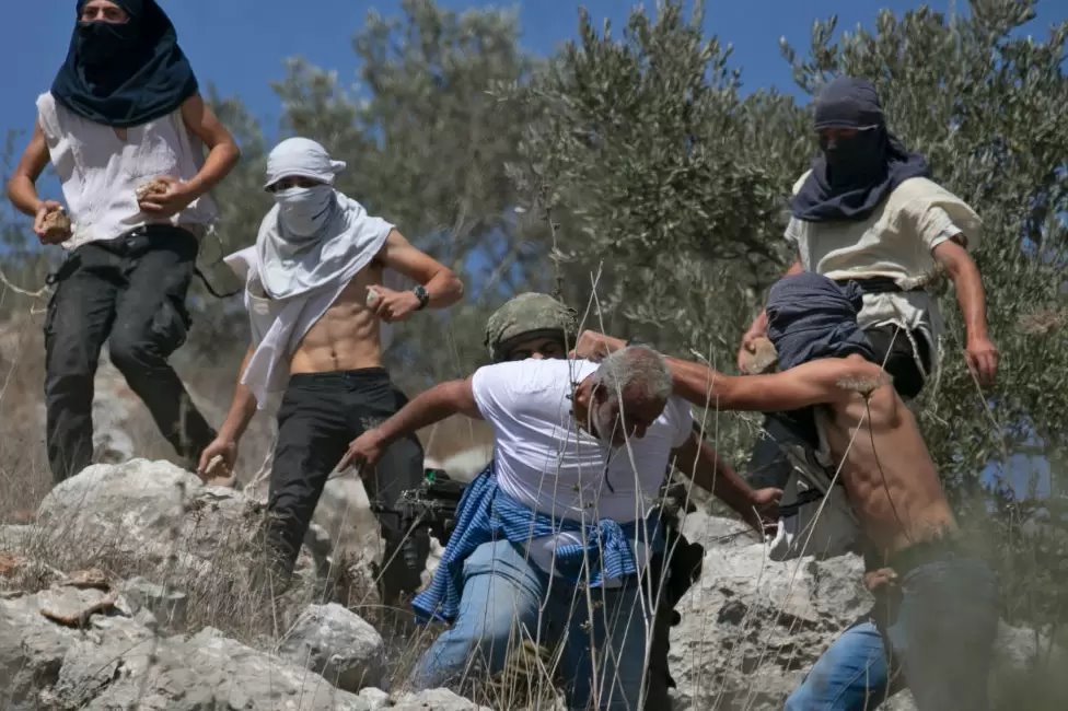 مستوطنون إسرائيليون ملثمون يهاجمون مزارعي الزيتون الفلسطينيين في الضفة الغربية، أكتوبر 2020