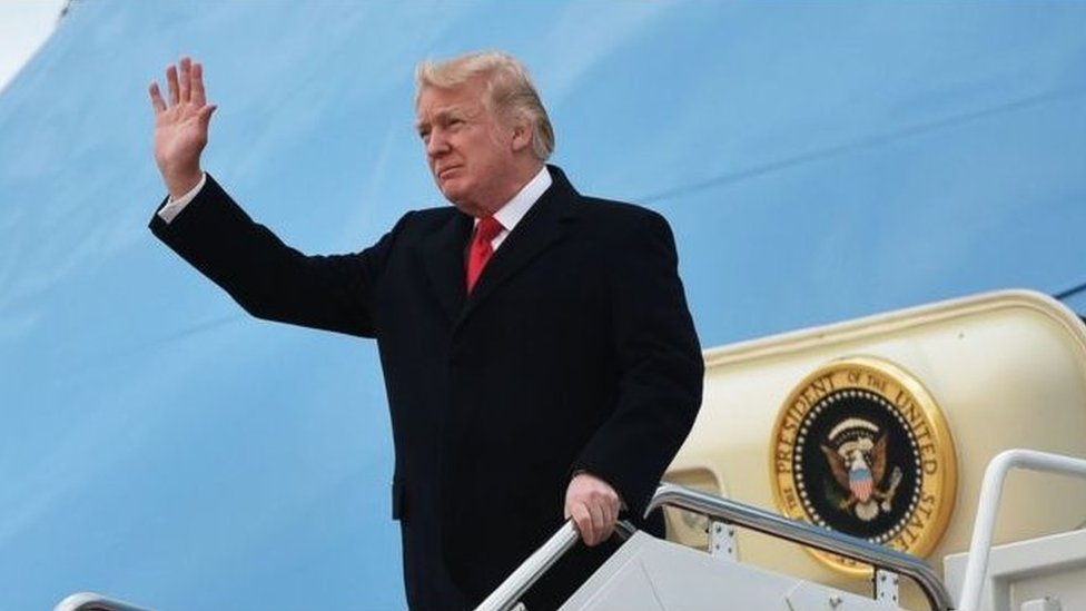 Президент Дональд Трамп машет рукой из самолета