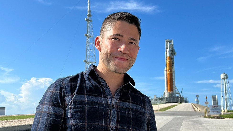 Ingeniero Luis Zea. Al fondo se ve la plataforma de lanzamiento de Artemis I con el cohete SLS y la nave Orión