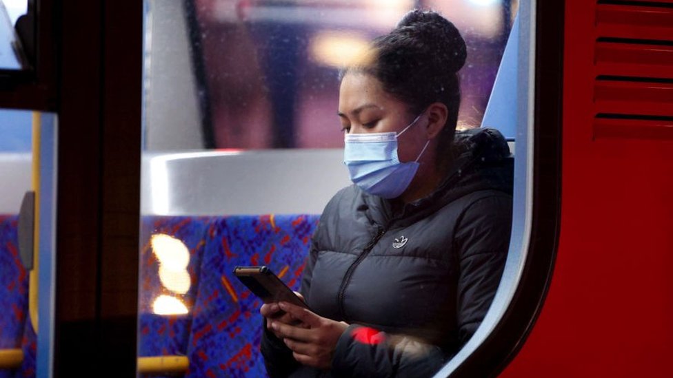 Uma mulher usando uma máscara facial para se proteger da covid-19 anda de ônibus em Piccadilly Circus em Londres, Reino Unido, em 31 de dezembro de 2021