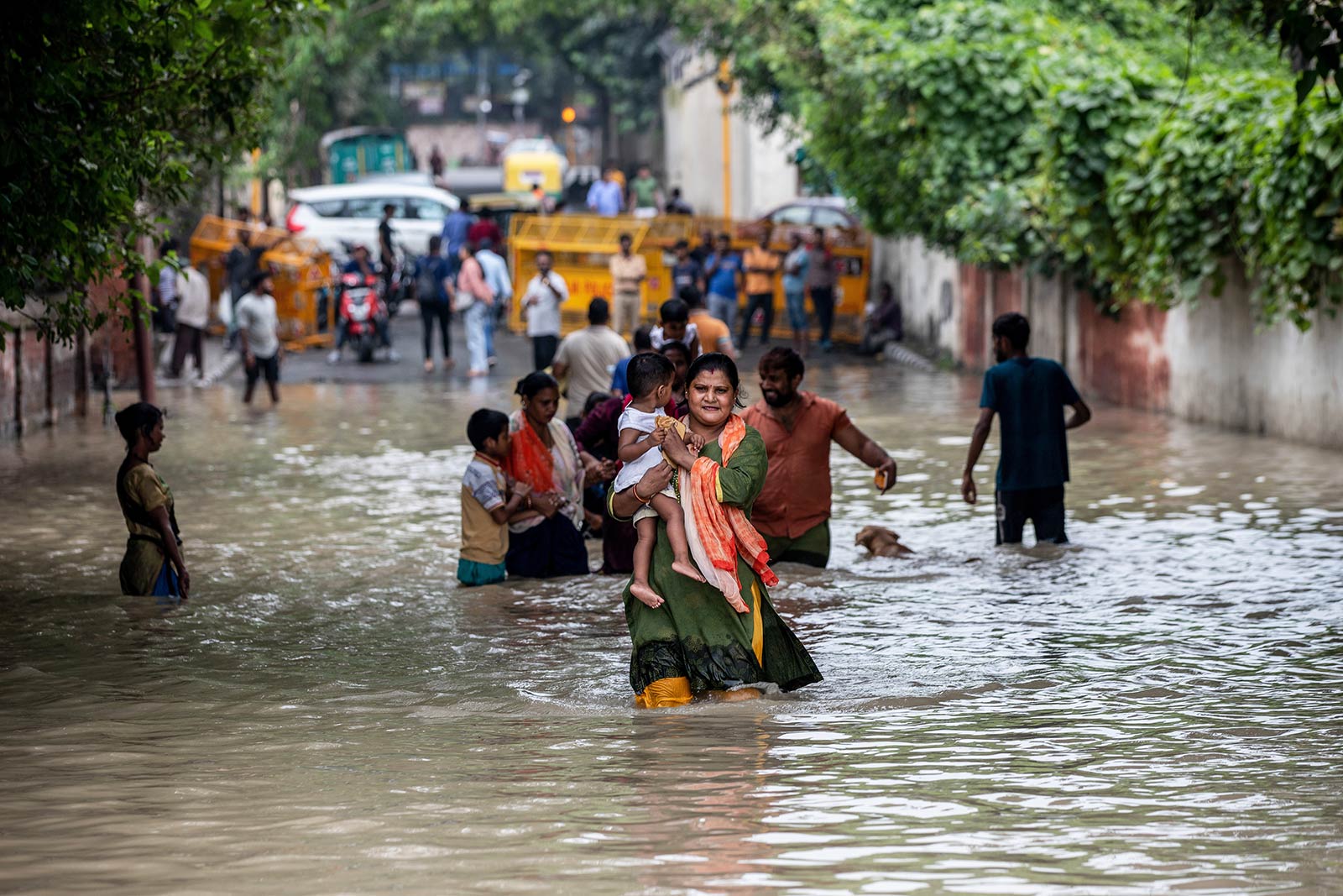 Families wade through flood waters after heavy monsoon rains in New Delhi, where people living close to the river Yamuna or low-lying areas were asked to evacuate their homes - 14 July 2023