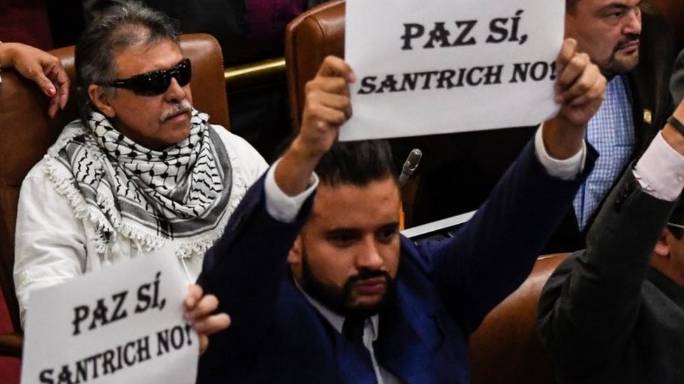 Хесус Сантрич занимает свое депутатское место в Колумбийском национальном конгрессе рядом с другими депутатами, которые протестуют против его присутствия в нижней палате в Боготе 12 июня 2019 г.
