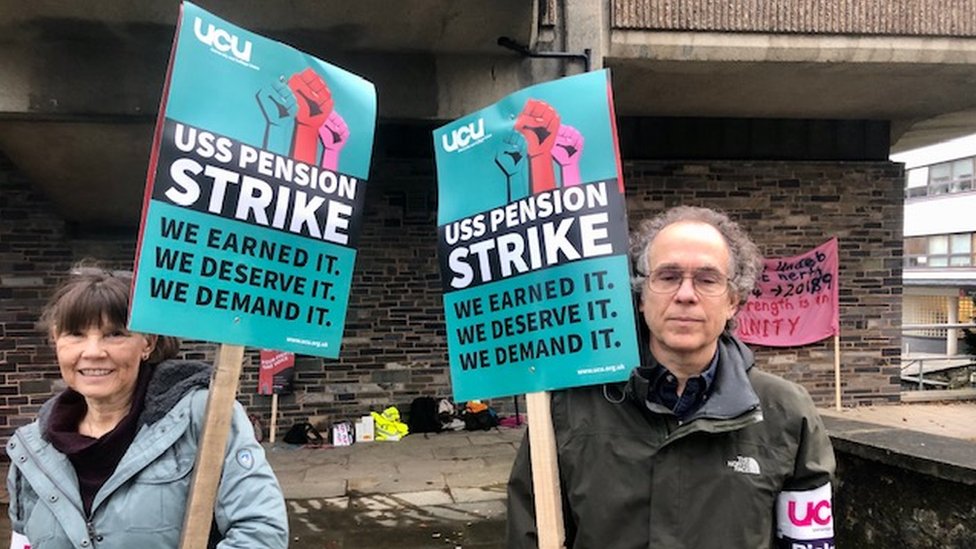 Два сотрудника держат плакаты в знак протеста