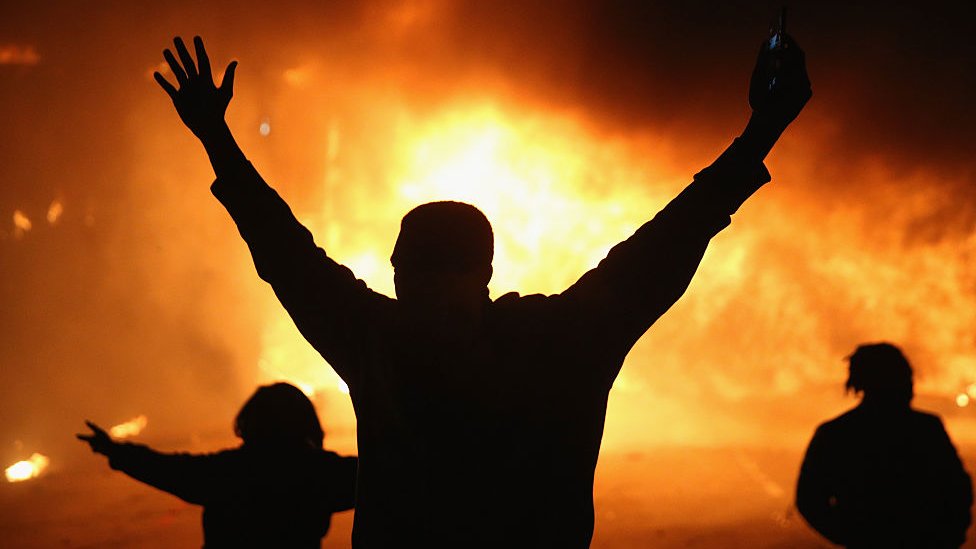 Un hombre levanta las manos frente a un fuego