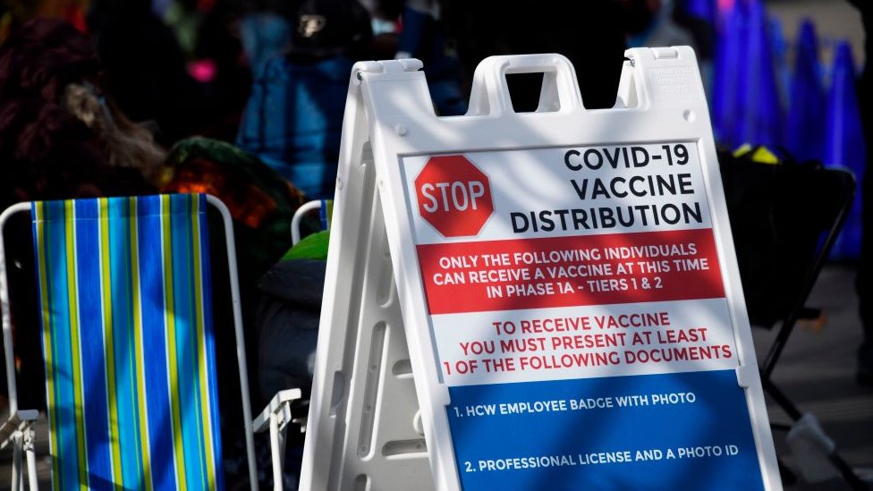 Cartaz em inglês aponta requisitos para a aplicação da vacina, como identidade com foto e licença profissional