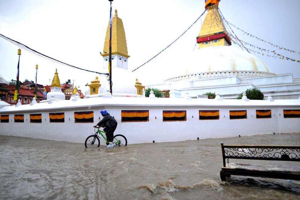 Велосипедист, путешествующий по затопленной воде на территории ступы Будханатх, объекта Всемирного наследия ЮНЕСКО, в Катманду, Непал, в четверг, 6 сентября 2018 г.
