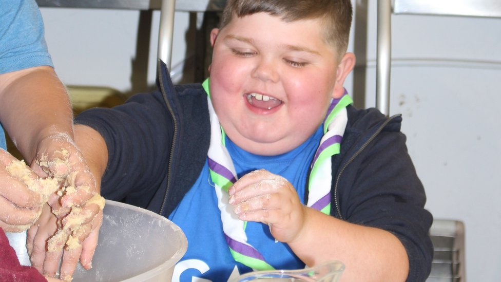 Мальчик окунает руку в миску для торта