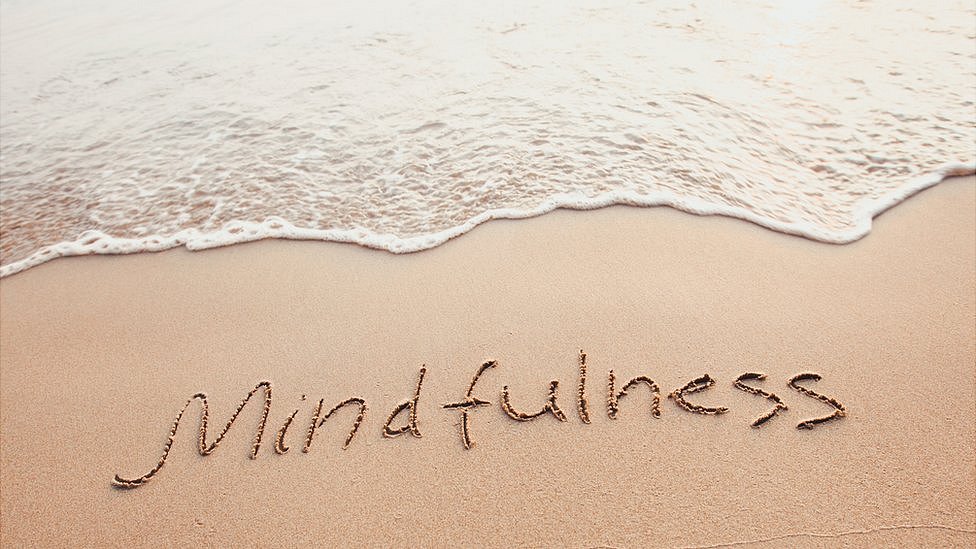 Playa con la palabra "mindfulness" escrita en la arena