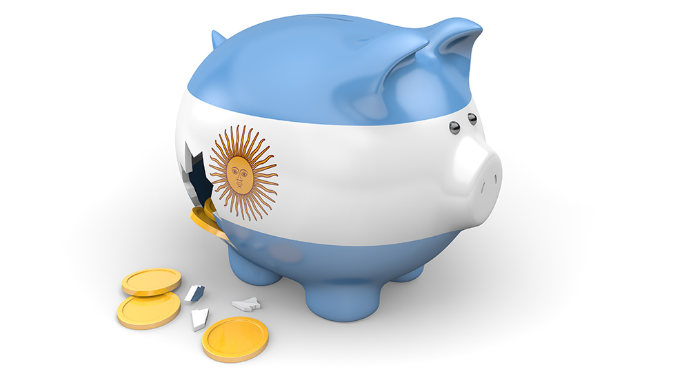 Cofre em formato de porquinho com as cores da bandeira argentina e moedas saindo por uma rachadura