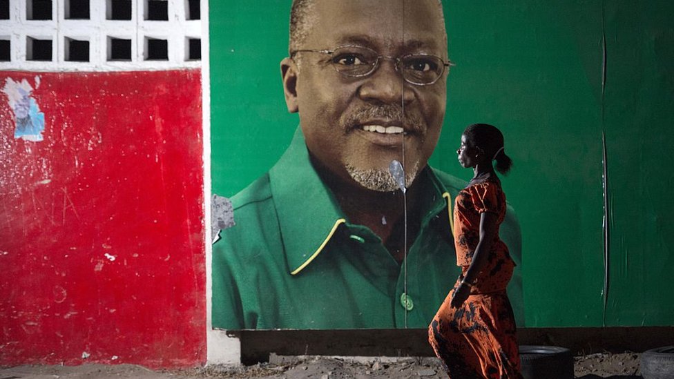 امرأة تمر على حائط عليه صورة الرئيس التنزاني ماغوفولي